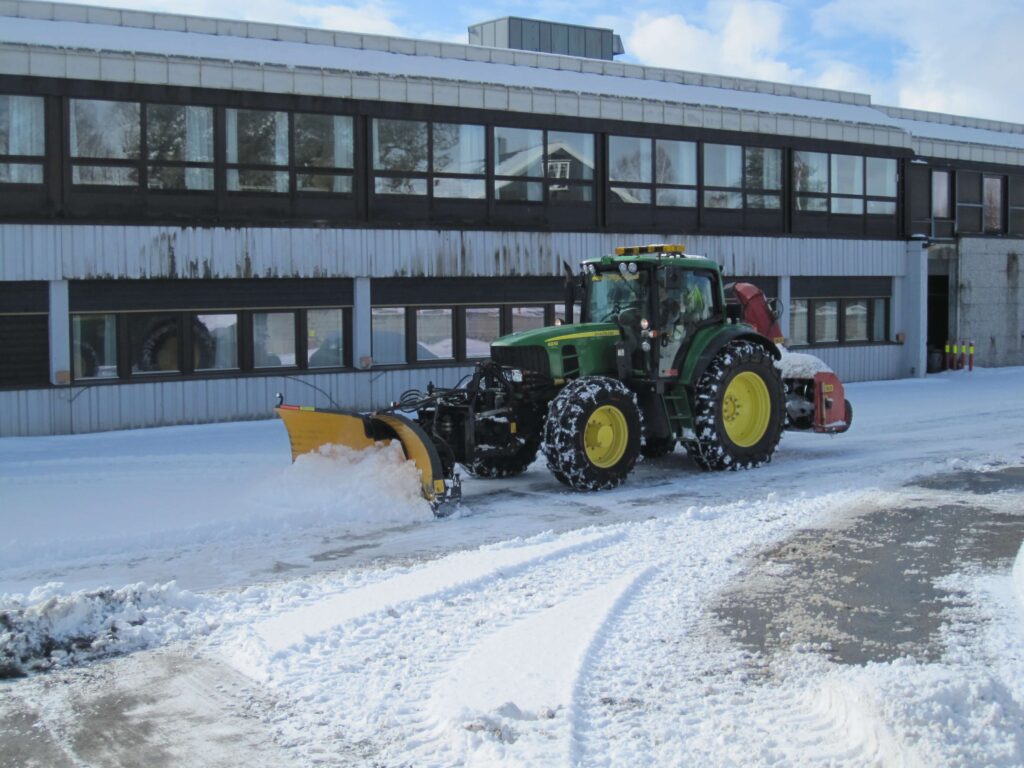 Traktor brøyter snø ved næringsbygg i Bærum