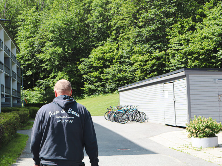 Gartner går gjennom grøntanlegg ved boligblokk